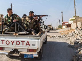 A Peshmerga soldier returns fire as his convoy drives through an area exposed to a sniper on November 8, 2016 in the town of Bashiqa, during street battles against ISIL.