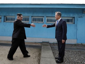 North Korean leader Kim Jong Un, left, prepares to shake hands with South Korean President Moon Jae-in over the military demarcation line at the border village of Panmunjom in Demilitarized Zone on April 27, 2018. (Korea Summit Press Pool via AP)