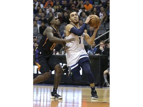 Minnesota Timberwolves guard Tyus Jones (1) drives to the basket past the defense of Phoenix Suns' Jawun Evans during the first half of an NBA basketball game, Saturday, Dec. 15, 2018, in Phoenix.