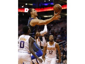 Dallas Mavericks forward Dwight Powell (7) drives between Phoenix Suns guard Jawun Evans and T.J. Warren (12) in the first half during an NBA basketball game, Thursday, Dec. 13, 2018, in Phoenix.