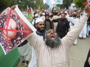 A Pakistani supporter of the Ahle Sunnat Wal Jamaat, a hardline religious party, holds a photo of Asia Bibi, a Christian, during a protest following the Supreme Court's decision to acquit her of blasphemy, in Islamabad on Nov. 2, 2018.