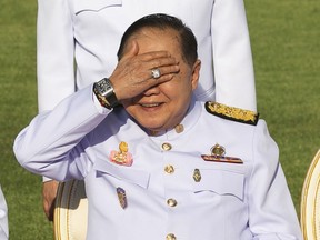 FILE - In this Dec. 4, 2017, file photo, Thailand's Deputy Prime Minister Prawit Wongsuwan raises his hand to shade his eyes from the sun while wearing a luxury watch and diamond ring during an official ceremony at the Government House. Thailand's National Anti-Corruption Commission has declared Prawit innocent of failing to declare his assets in a case that sparked a scandal when he was spotted wearing a number of luxury watches that he would not easily be able to afford on his government salary.