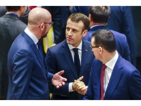 French President Emmanuel Macron, center, speaks with Belgian Prime Minister Charles Michel, left, during a round table meeting at an EU summit in Brussels, Friday, Dec. 14, 2018. European Union leaders have offered Theresa May sympathy but no promises, as the British prime minister seeks a lifeline that could help her sell her Brexit divorce deal to a hostile U.K. Parliament.