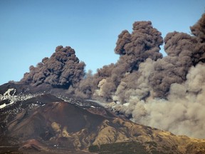 A smoke column comes out of the Etna volcano in Catania, Italy, Monday, Dec. 24, 2018. The Mount Etna observatory says lava and ash are spewing from a new fracture on the active Sicilian volcano amid an unusually high level of seismic activity.
