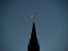 Ottawa ran a small surplus of $92 million through the first seven months of its fiscal year, compared with a deficit of nearly $6.6 billion in the same period last year as revenue has increased faster than spending. The Canadian Flag is illuminated by morning light atop the Peace Tower on Parliament Hill in Ottawa on Monday, Sept. 17, 2018.