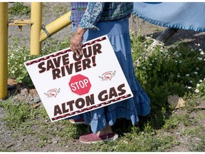 Mi'kmaq activist Ducie Howe carries a sign at an encampment near the Shubenacadie River, a 72-kilometre tidal river that cuts through the middle of Nova Scotia and flows into the Bay of Fundy, in Fort Ellis, N.S. on July 31, 2018. A controversial natural gas storage project north of Halifax is facing more delays. Alton Natural Gas had planned to start the process of creating huge underground caverns east of Alton, N.S., before the end of the year. But the company now says that plan has been put on hold because of "project and regulatory planning."