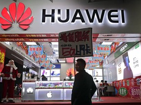 A worker holds a sign promoting a sale for Huawei 5G internet services at a mobile phones retail shop in Shenzhen in south China's Guangdong province, Tuesday, Dec. 18, 2018. A senior Huawei Canada official says there would be catastrophic fallout if the company were caught conducting espionage on behalf of Beijing.