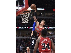 Chicago Bulls forward Lauri Markkanen (24) goes up for a dunk over Orlando Magic center Nikola Vucevic (9) during the second half of an NBA basketball game Friday, Dec. 21, 2018, in Chicago. The Bulls won 90-80.