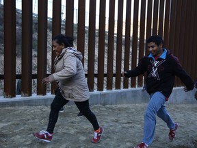 Honduran migrants run away from Border Patrol agents as they try to cross over the U.S. border wall to San Diego, California, from Tijuana, Mexico, Saturday, Dec. 15, 2018.