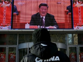 A man stands and watches a large screen during President Xi Jinping's speech at a grand gathering to celebrate the 40th anniversary of China's reform and opening-up in Beijing on December 18, 2018 in Harbin, China.