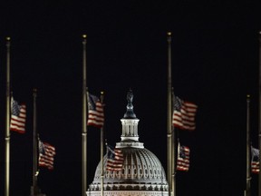 The U.S. Capitol Dome is seen beyond American Flags around the the base of the Washington Monument in Washington, early Saturday, Dec. 22, 2018. The American Flags are at half-staff to honor of former President George H.W. Bush. Hundreds of thousands of federal workers faced a partial government shutdown early Saturday after Democrats refused to meet President Donald Trump's demands for $5 billion to start erecting a border wall with Mexico. Overall, more than 800,000 federal employees would see their jobs disrupted, including more than half who would be forced to continue working without pay.