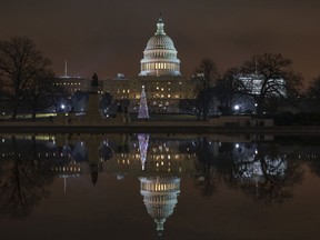The Capitol is mirrored in the Reflecting Pool in Washington, as a partial government shutdown heads into a second week, Friday night, Dec. 28, 2018. Both chambers of Congress are gone, likely leaving the impasse till next week when the Democrats take control of the House of Representatives.