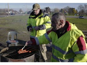 Demonstrators wearing their yellow vests prepare sausages for lunch on a traffic circle, Tuesday, Dec. 11, 2018 in Douai, northern France. President Emmanuel Macron broke his silence Monday on the exceptional protests shaking France and his presidency, promising broad tax relief for struggling workers and pensioners -- and acknowledging his own responsibility in fueling the nation's anger.
