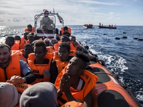 In this Friday, Dec. 21, 2018, photo, migrants sit in a rubber dinghy after Proactiva Open Arms, a Spanish NGO, spotted and rescued them in the Central Mediterranean Sea at 45 miles (72 kilometers) from Al Khums, Lybia. The Spanish NGO Open Arms have rescued about 300 migrants from 3 boats crossing the Mediterranean from North Africa to Europe on Friday.