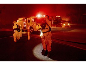 In this file photo from Thursday, Nov. 8, 2018, firefighter Adrien Mahnke pauses while battling the Camp Fire as it tears through Paradise, Calif. A report on firefighter injuries in a deadly Northern California wildfire details harrowing conditions they faced and a few close calls with death. The report released Thursday, Dec. 13, 2018 by the California Department of Forestry and Fire Protection said the Camp Fire overtook three firefighters trying to set a backfire Nov. 8 to stop the blaze.