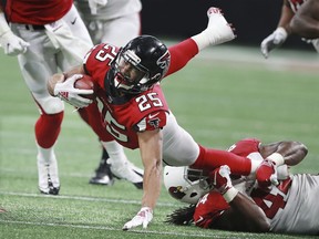 Atlanta Falcons running back Ito Smith dives forward for yardage with Arizona Cardinals defensive end Markus Golden making the tackle during the second quarter of an NFL football game on Sunday, Dec 16, 2018, in Atlanta.
