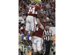 Alabama offensive lineman Jedrick Wills Jr. (74) lifts running back Damien Harris (34) after Harris scored a touchdown during the first half of the Orange Bowl NCAA college football game against Oklahoma, Saturday, Dec. 29, 2018, in Miami Gardens, Fla.