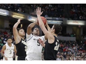 Notre Dame's D.J. Harvey (5) puts puts up a shot against Purdue's Carsen Edwards (3) and Grady Eifert (24) during the first half of an NCAA college basketball game, Saturday, Dec. 15, 2018, in Indianapolis.