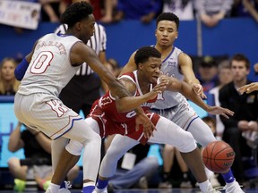Kansas' Marcus Garrett (0) and Devon Dotson try to strip the ball from South Dakota's Stanley Umude, center, during the first half of an NCAA college basketball game Tuesday, Dec. 18, 2018, in Lawrence, Kan.