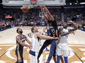 New Orleans Pelicans forward Anthony Davis (23) dunks over Dallas Mavericks forwards Dorian Finney-Smith (10) and Dirk Nowitzki during the first half of an NBA basketball game in New Orleans, Friday, Dec. 28, 2018.