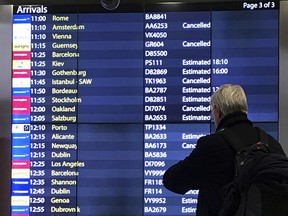 A passenger checks an arrivals board at Gatwick Airport in England, Friday, Dec. 21, 2018.