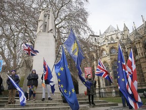 Anti-Brexit demonstrators wave flags outside the houses of Parliament in London, Wednesday Dec. 19, 2018.
