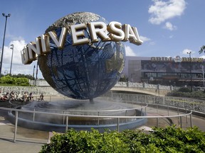 FILE- In this Oct. 22, 2015 file photo, park guests relax and cool off with a water mist under the globe at Universal Studios City Walk in Orlando, Fla. A lawsuit brought by a Guatemalan family whose father died after going on a ride says Universal Orlando Resort should have put warning signs in Spanish.