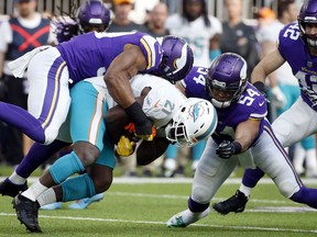 Miami Dolphins running back Frank Gore (21) is tackled by Minnesota Vikings defensive end Danielle Hunter, left, and middle linebacker Eric Kendricks (54) during the first half of an NFL football game, Sunday, Dec. 16, 2018, in Minneapolis.