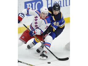 St. Louis Blues' Ivan Barbashev (49), of Russia, reaches for the puck with New York Rangers' Brady Skjei (76) defending during the first period of an NHL hockey game Monday, Dec. 31, 2018, in St. Louis.