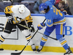 St. Louis Blues' Jordan Nolan (71) reaches for the puck with Pittsburgh Penguins' Tanner Pearson (14) during the first period of an NHL hockey game, Saturday, Dec. 29, 2018, in St. Louis.