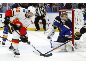 St. Louis Blues goaltender Jake Allen, right, watches as Calgary Flames' Alan Quine reaches for the puck during the first period of an NHL hockey game Sunday, Dec. 16, 2018, in St. Louis.
