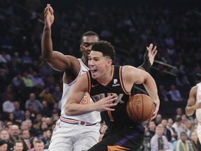 CORRECTS ID TO DEVIN BOOKER NOT AUSTIN RIVERS Phoenix Suns' Devin Booker (1) drives past New York Knicks' Noah Vonleh during the first half of an NBA basketball game Monday, Dec. 17, 2018, in New York.