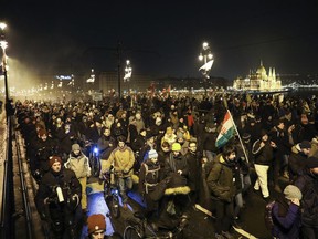 Anti-government demonstrators march across Margaret Bridge over the River Danube with the Parliament building in the background, in Budapest, Hungary, Sunday, Dec. 16, 2018. Protesters are demonstrating against recent changes to the labour laws.