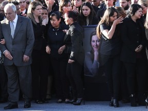 Relatives and friends stand surrounding the urn with ashes of opposition Puebla state Gov. Martha Erika Alonso during a farewell ceremony in Puebla City, southeast of Mexico, Tuesday, Dec. 25, 2018. Mexico has invited experts from the U.S. National Transportation Safety Board to investigate a helicopter crash that killed the governor, her husband, two pilots and a third passenger.