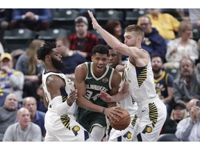 Indiana Pacers guard Tyreke Evans (12) and forward Domantas Sabonis (11) trap Milwaukee Bucks forward Giannis Antetokounmpo (34) during the first half of an NBA basketball game in Indianapolis, Wednesday, Dec. 12, 2018.