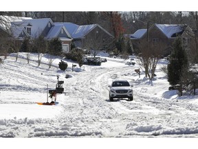 A car travels down a snow covered street in a neighborhood in Greensboro, N.C., Tuesday, Dec. 11, 2018. Several Southern states hit hard by a wintry storm were gradually warming Tuesday, but forecasters warned that temperatures in many areas will plunge below freezing again Tuesday night. That will refreeze the melting snow, making some roads treacherous.