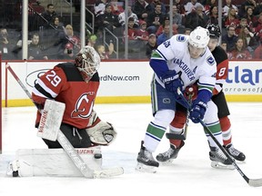 New Jersey Devils goaltender Mackenzie Blackwood (29) makes a save as New Jersey Devils defenseman Will Butcher (8) checks Vancouver Canucks center Bo Horvat (53) during the first period of an NHL hockey game Monday, Dec. 31, 2018, in Newark, N.J. Blackwood stopped 25 shots as the Devils defeated the Canucks 4-0.