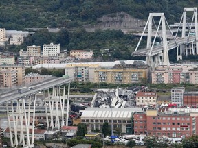 FILE - In this Tuesday, Aug. 14, 2018 file photo cars are blocked on the Morandi highway bridge after a section of it collapsed, in Genoa, northern Italy. A large section of the bridge collapsed over an industrial area in the Italian city of Genova during a sudden and violent storm, leaving vehicles crushed in rubble below.