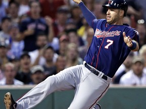 FILE - In this June 29, 2017, file photo, Minnesota Twins' Joe Mauer starts to slide as he scores on a double by Jorge Polanco during the fourth inning of the team's baseball game against the Boston Red Sox, at Fenway Park in Boston. The Minnesota Twins will retire Joe Mauer's No. 7 jersey next season, moving swiftly with the prestigious honor for the six-time All-Star who recently finished a 15-year major league career. The Twins surprised Mauer with the announcement while he was being celebrated at an all-student assembly at his alma mater Cretin-Derham Hall High School on Tuesday, Dec. 18, 2018.