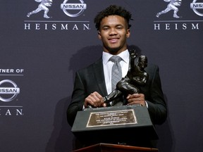 FILE - In this Dec. 8, 2018, file photo, Oklahoma quarterback Kyler Murray holds the Heisman Trophy after winning the award in New York. The latest statistical surge has been led by the quarterbacks who will play in the Orange Bowl semifinal on Jan. 29, when No. 1 Alabama faces No. 4 Oklahoma. Both Heisman Trophy winner Murray (205.72) of Oklahoma and Alabama's Tua Tagovailoa (202.30) are on pace to break the record for passer efficiency rating set by former Sooners quarterback Baker Mayfield (198.92) last season.