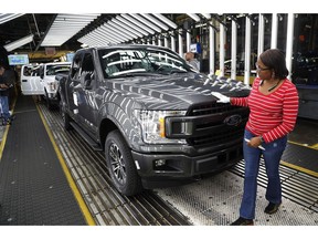 FILE- In this Sept. 27, 2018, file photo United Auto Workers' assemblyman Kelly Coman gives a final look to an assembled 2018 Ford F-150 truck on the assembly line at the Ford Rouge assembly plant in Dearborn, Mich. On Friday, Dec. 14, the Federal Reserve reports on U.S. industrial production for November.
