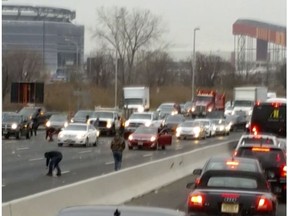This screen shot from a video provided by Danielle Shah shows people picking up cash that spilled from an armored truck onto the highway in East Rutherford, N.J., near MetLife Stadium, Thursday, Dec. 13, 2018. Police say the incident caused multiple crashes as motorists stopped to grab the money from the truck that authorities say apparently had an issue with the locking device on one of its doors.
