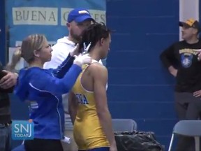 In this image taken from a Wednesday, Dec. 19, 2018 video provided by SNJTODAY.COM, Buena Regional High School wrestler Andrew Johnson gets his hair cut courtside minutes before his match in Buena, N.J., after a referee told Johnson he would forfeit his bout if he didn't have his dreadlocks cut off. Johnson went on to win the match after a SNJ Today reporter tweeted video if the incident, the state's Interscholastic Athletic Association says they are recommending the referee not be assigned to any event until the matter has been reviewed more thoroughly.