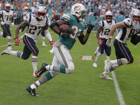 FILE - In this Dec. 9, 2018, file photo, Miami Dolphins running back Kenyan Drake (32) runs for a touchdown during the second half of an NFL football game against the New England Patriots, in Miami Gardens, Fla. "I mean honestly, I'm sitting before you all and I still don't believe it," Drake said during interviews after the improbable conclusion sent New England to its fifth loss in the last six visits to South Florida. "I just saw it was Gronk in front of me and I was just like, 'Look, I've got somewhere to be.' So I had to get in the end zone."