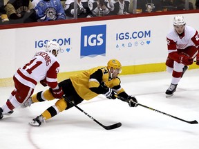 Pittsburgh Penguins' Tanner Pearson (14) gets off a pass as he falls to the ice with Detroit Red Wings' Luke Glendening (41) defending during the first period of an NHL hockey game in Pittsburgh, Thursday, Dec. 27, 2018.