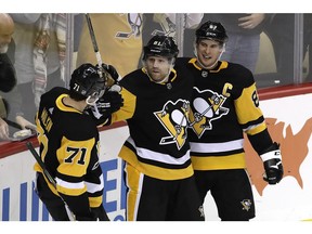 Pittsburgh Penguins' Phil Kessel (81) celebrates his winning goal with Sidney Crosby (87) and Evgeni Malkin (71) in the overtime period of an NHL hockey game against the Los Angeles Kings in Pittsburgh, Saturday, Dec. 15, 2018.