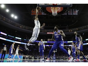 Brooklyn Nets' Jarrett Allen, left, goes up for a dunk as Philadelphia 76ers' Joel Embiid looks on during the first half of an NBA basketball game, Wednesday, Dec. 12, 2018, in Philadelphia.