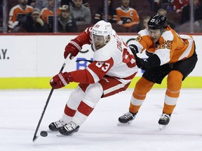 Philadelphia Flyers' James van Riemsdyk, right, hooks Detroit Red Wings' Trevor Daley during the first period of an NHL hockey game, Tuesday, Dec. 18, 2018, in Philadelphia.