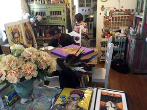 In this Thursday, April 5, 2018 photo artist Moises Salcedo (left) of Albuquerque, who goes by the name El Moises, sits amid his artwork at his home and studio in Albuquerque, N.M. on Thursday, April 5, 2018. He and celebrated Chicano author Rudolfo Anaya crafted the book that follows the adventures in English and Spanish of a tiny owl named Oli who longs to read on his own, even as he skips school and tangles with a cast of conniving animal characters in the hills and skies of northern New Mexico. A sequel is planned to address concerns about bullying.