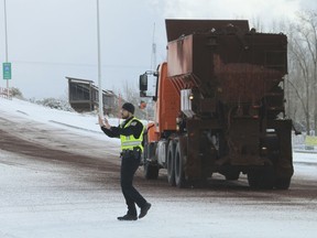 A Bernalillo police officer directs traffic as a state transportation truck spreads cinder on an icy roadway in Bernalillo, N.M., on Friday, Dec. 28, 2018. The National Weather Service issued a blizzard warning for Albuquerque through Saturday morning and most of the rest of New Mexico is under a winter storm warning through Saturday morning.